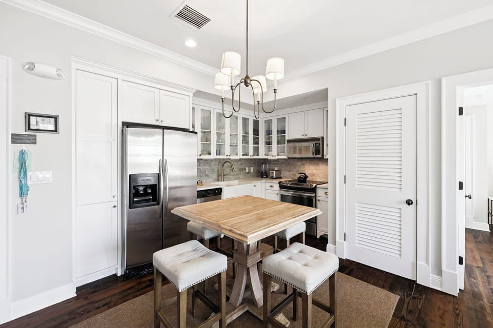 Your elegant kitchen invites culinary adventures with stainless steel appliances, pristine white cabinetry, and a cozy island perfect for morning coffee.
