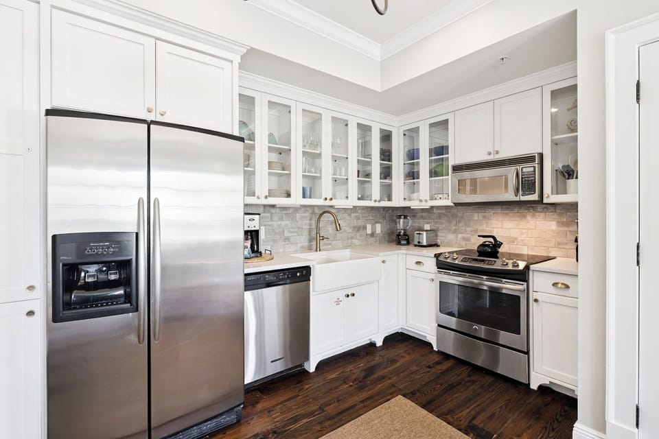 Your gourmet kitchen awaits with gleaming stainless steel appliances, marble countertops, and glass-front cabinets perfect for preparing memorable meals.