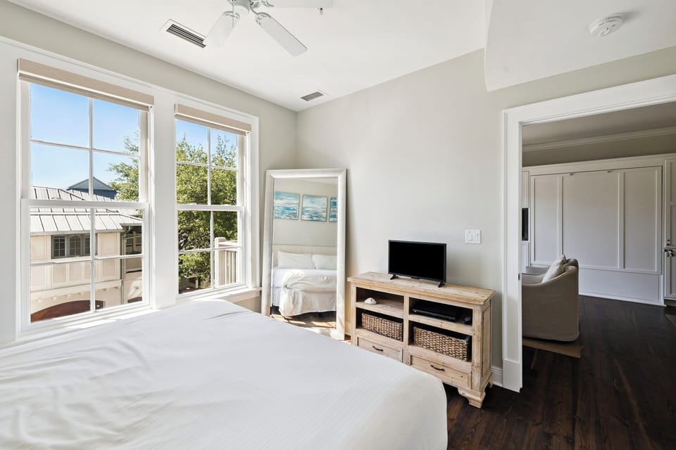 Your bright bedroom features a cozy Murphy bed, entertainment center, and peaceful neighborhood views through large windows.