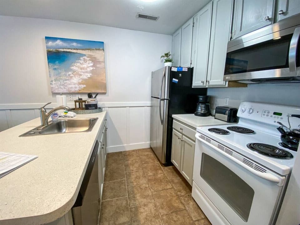 Fully equipped kitchen with modern appliances and beachy charm, ready for cooking and casual dining.