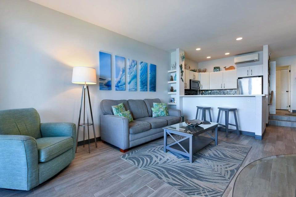 Relax on the sleeper sofa surrounded by wave art canvas prints, with easy sightlines to the open-concept kitchen and breakfast bar.
