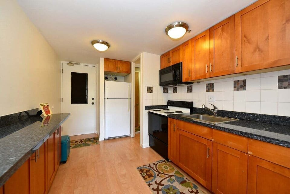 Fully equipped kitchen with warm wood finishes, stainless steel stove and microwave, and a clean, functional design