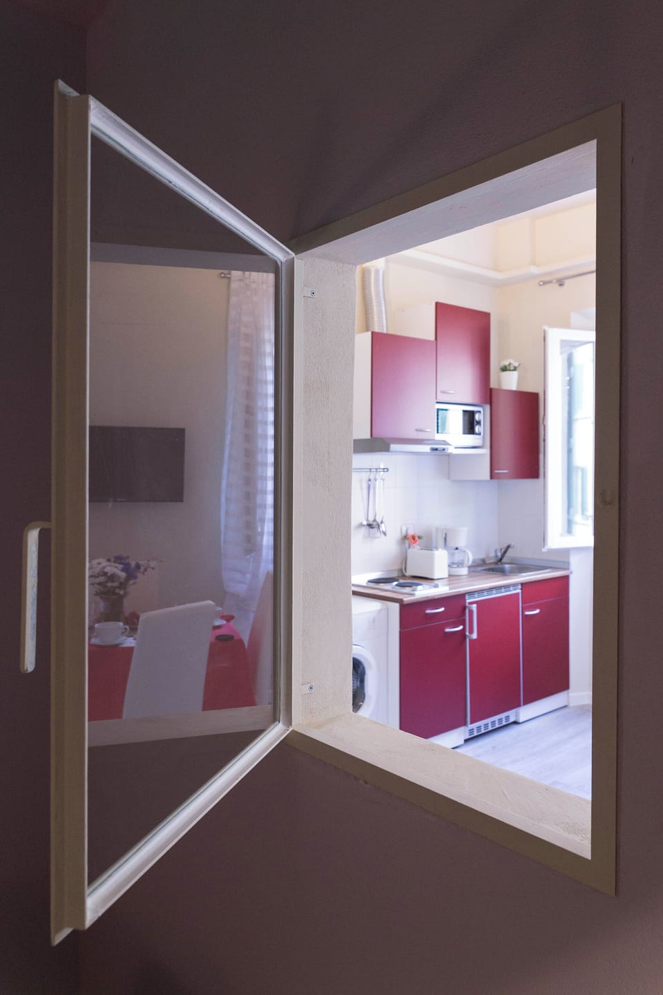 Small window in bedroom adds extra light with curtains for privacy.