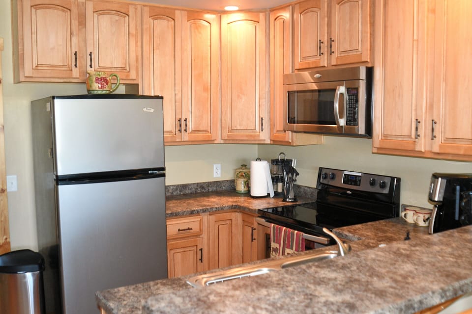 Clean kitchen with refrigerator/freezer, stovetop, oven, microwave, coffeemaker