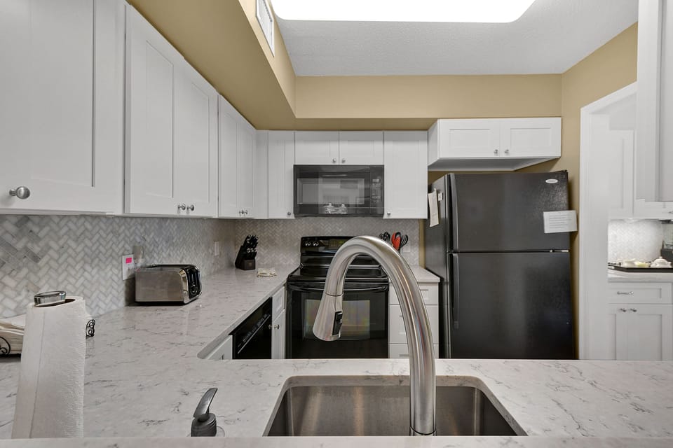 Kitchen Counter and Sink - Stone counter, sink, dishwasher, and stainless refrigerator complete the kitchen workspace.