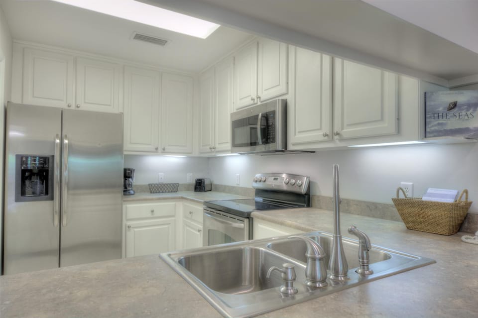 Kitchen Counter and Fridge View - Sink, prep space, and stainless refrigerator round out the practical kitchen setup.