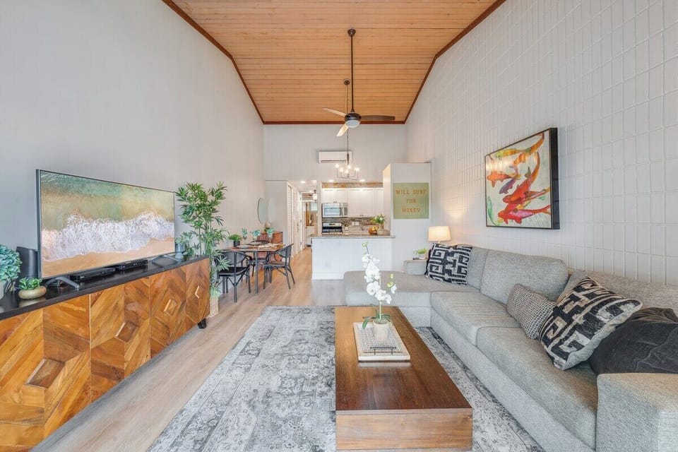 Unwind in a spacious lounge featuring a sleek sectional, wood accents, and natural light — perfect for relaxing or entertaining.