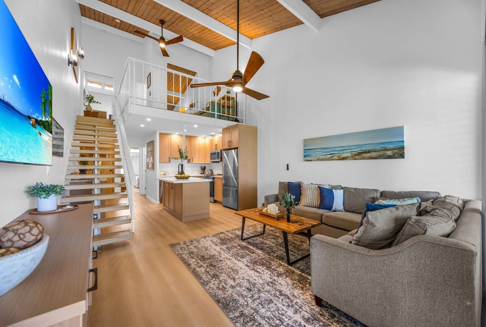 Experience the wow factor of soaring vaulted ceilings and a unique, custom spiral staircase leading to a loft space. This incredible open-concept layout includes the modern kitchen and living room, creating a grand, airy feel for your stay