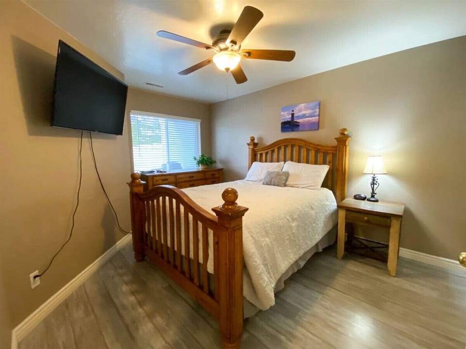 Bedroom retreat with warm wooden accents, soft bedding, and a mounted TV for relaxation
