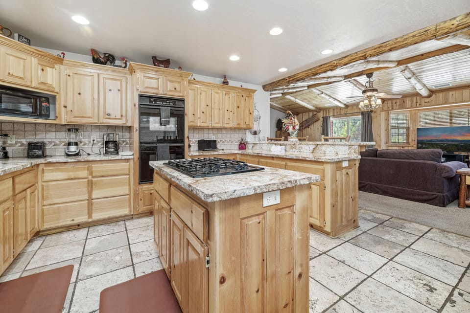 Spacous Kitchen - This kitchen is spacious for dining, cooking, & gathering! Beautiful Marble Countertops throughout with pine wood cabinets and a dining table that seats 6 with additional bar seating for 4 people. All cooking & eating necessities are supplied.