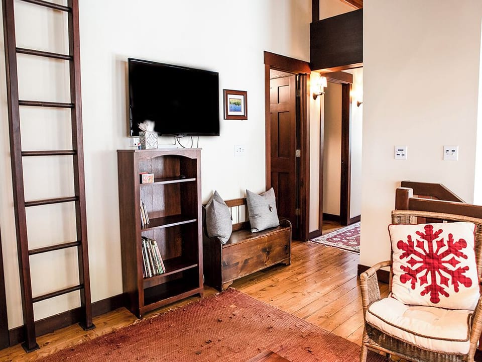 Upstairs Loft - A photo of the upstairs loft, showing the tv and hallway to twin bunkrooms and common bathroom.