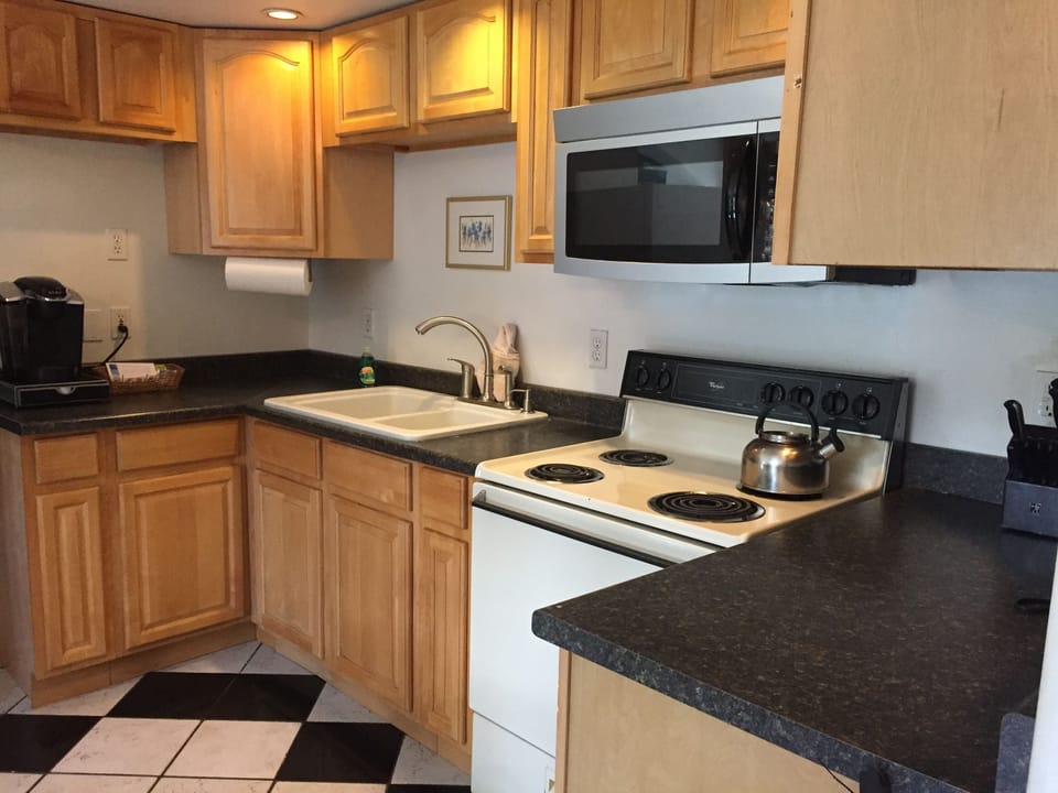 Fully stocked kitchen with dishes, flatware and pans
