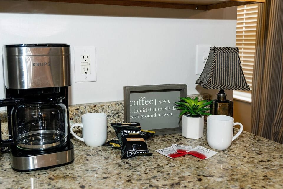 Krups drip coffee maker with coffee, creamer, sugar, and tea on us.
