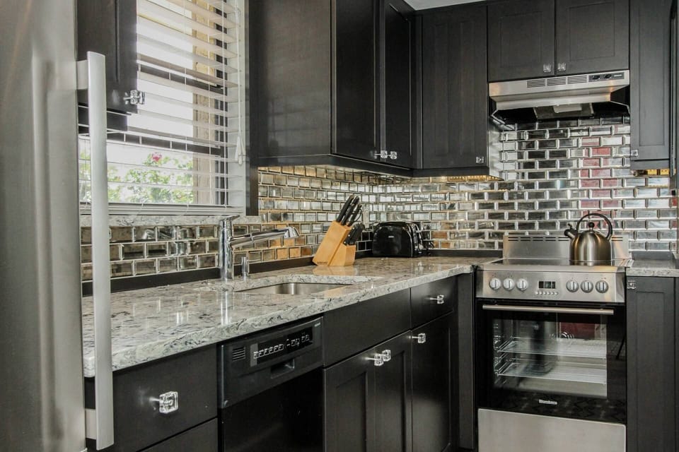 Enjoy this dream kitchen w/custom cabinets, quartz counter tops, & unique mirrored subway tile backsplash