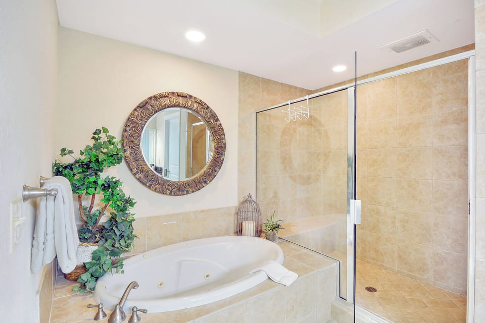 Primary Bath with Tub and Walk-In Shower - Ensuite bathroom with soaking tub, walk-in shower, single vanity, tile floors, and warm finishes.