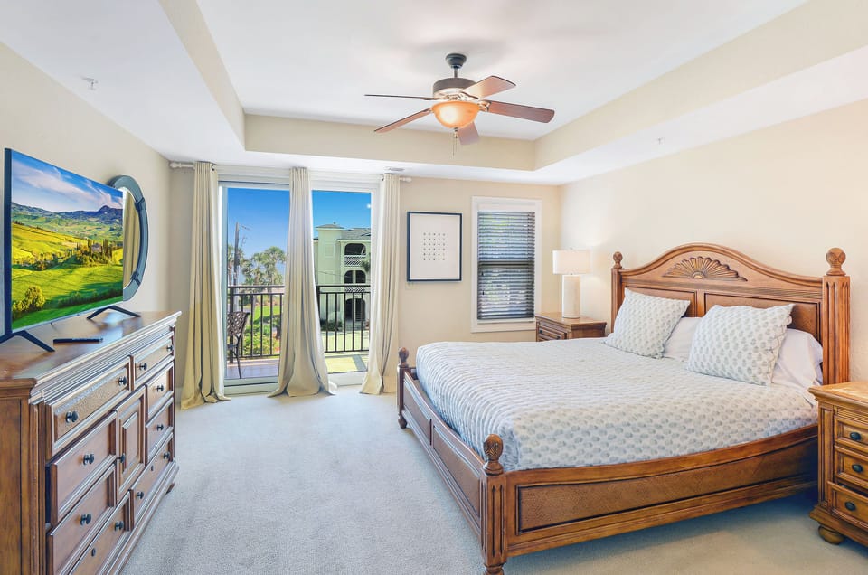 King Bedroom with Ocean-Facing Balcony - Primary bedroom with king bed, Smart TV, ceiling fan, and direct balcony access.