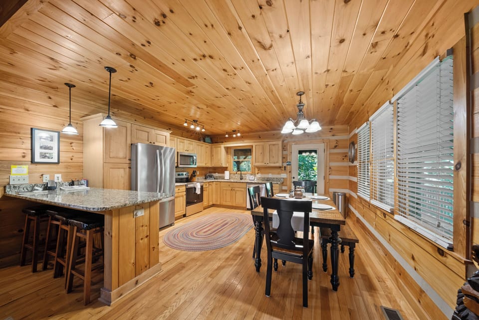 Gather the whole crew around the rustic wood dining table at Uncle Johns Cabin, with wooded views just beyond the deck door.