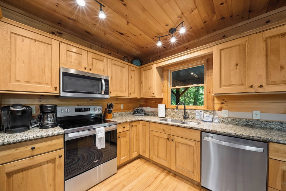 A fully equipped kitchen at Uncle Johns Cabin, where knotty pine and granite make cooking feel like part of the getaway.