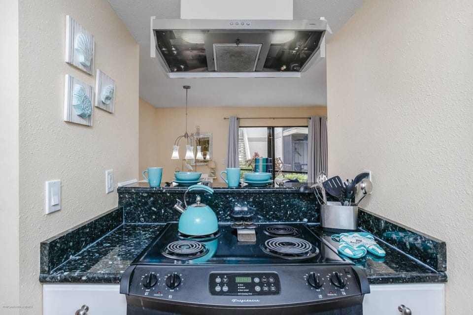 Modern kitchen with granite counters stocked with dishes, glasses, pots and pans