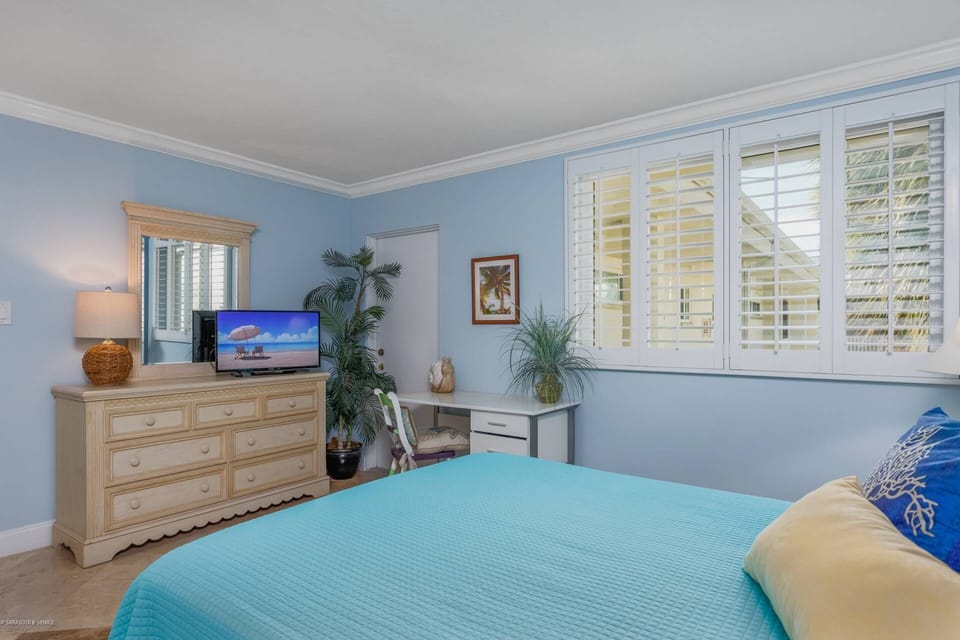 Guest queen bedroom with TV, closet and en-suite bath.  Close the plantation shutters to sleep in when you choose.