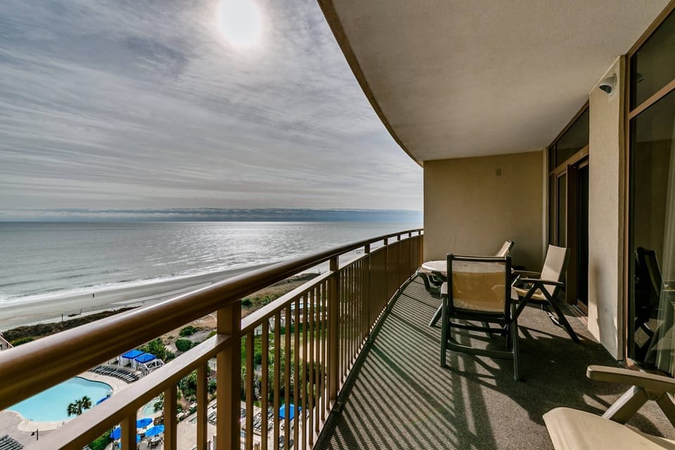 Breathtaking 11th-floor balcony view — watch the sun play hide-and-seek behind the clouds over the ocean.