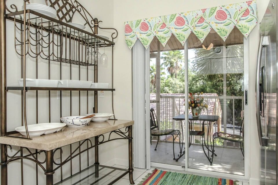 Sliding glass doors (w/custom window treatments) lead to screened front lanai w/bistro set for outdoor dining.