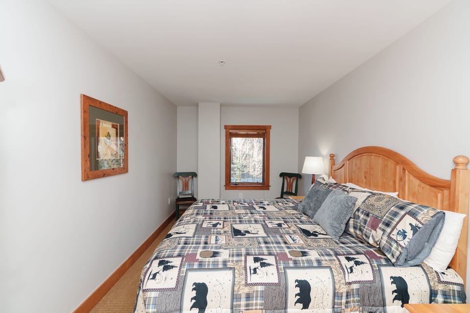 Cozy bedroom with rustic charm featuring a comfortable bed dressed in wilderness-themed bedding and warm wood accents for your mountain getaway.