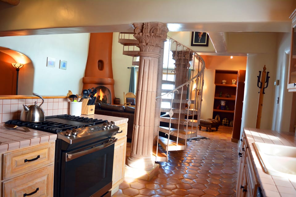 View from kitchen to wood burning fireplace, romantic spiral staircase and TV area