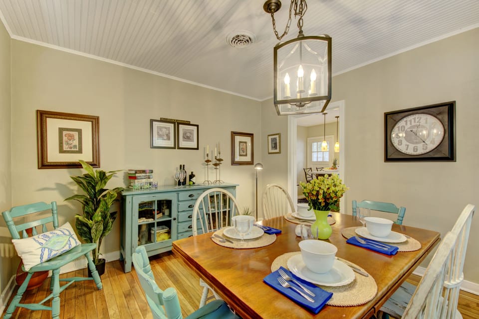 Dining Table and Living Room View - Second dining angle shows table seating beside the living room with hardwood floors and original cottage details.