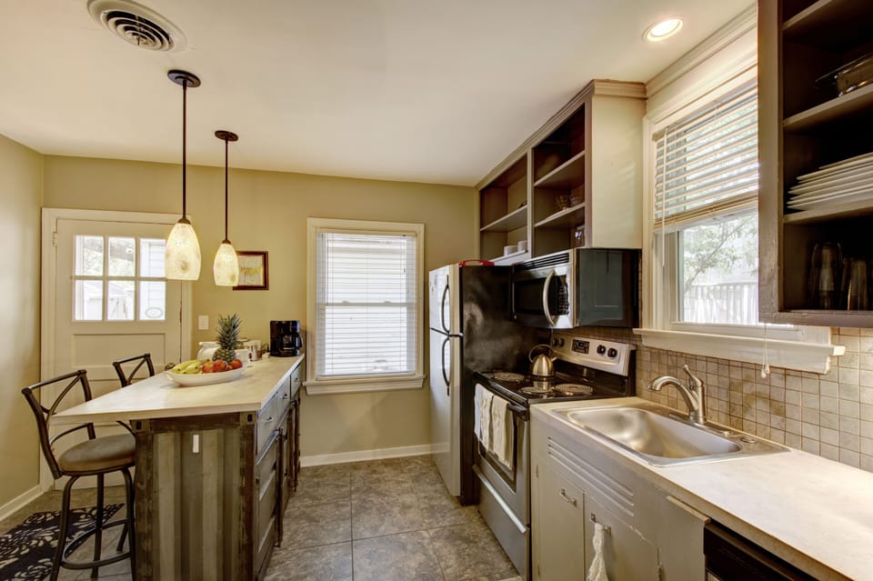 Kitchen Range and Sink View - Kitchen view shows the gas range, sink, dishwasher, open shelving, and breakfast bar seating.