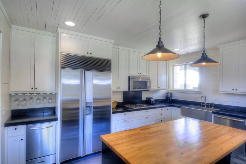 Kitchen Appliances And Butcher-Block Island - The double-door fridge, stainless range, microwave, island, and prep space keep meals practical for a full house.