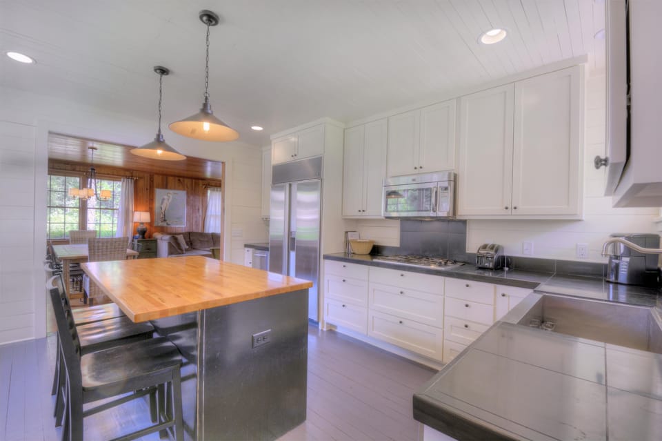 Kitchen Island With Stainless Appliances - The kitchen has a butcher-block island, stainless appliances, and bar seating for cooking, serving, and casual meals.