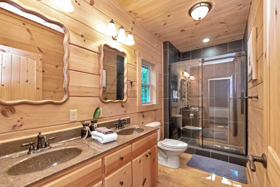 Pine-wrapped walls meet a sleek tiled walk-in shower at The Watchtower. Double sinks make mornings easy for the whole crew.