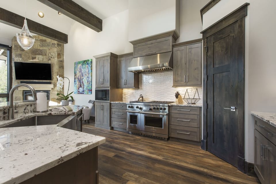 View into the kitchen with double oven, large sink, dishwasher, coffee maker, toaster oven, toaster, microwave, and refrigerator.