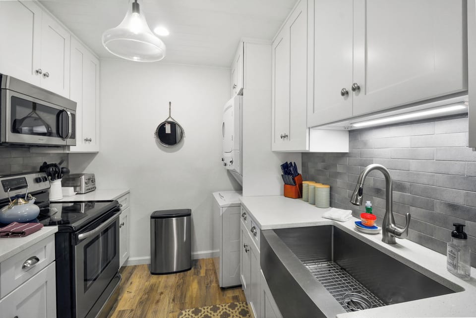 Kitchen – Ocean Walk J-11 - Cook with ease in this bright, well-stocked kitchen featuring stainless appliances, subway tile, and a deep farmhouse sink. Whether you're whipping up shrimp and grits or pouring wine, everything’s within reach.