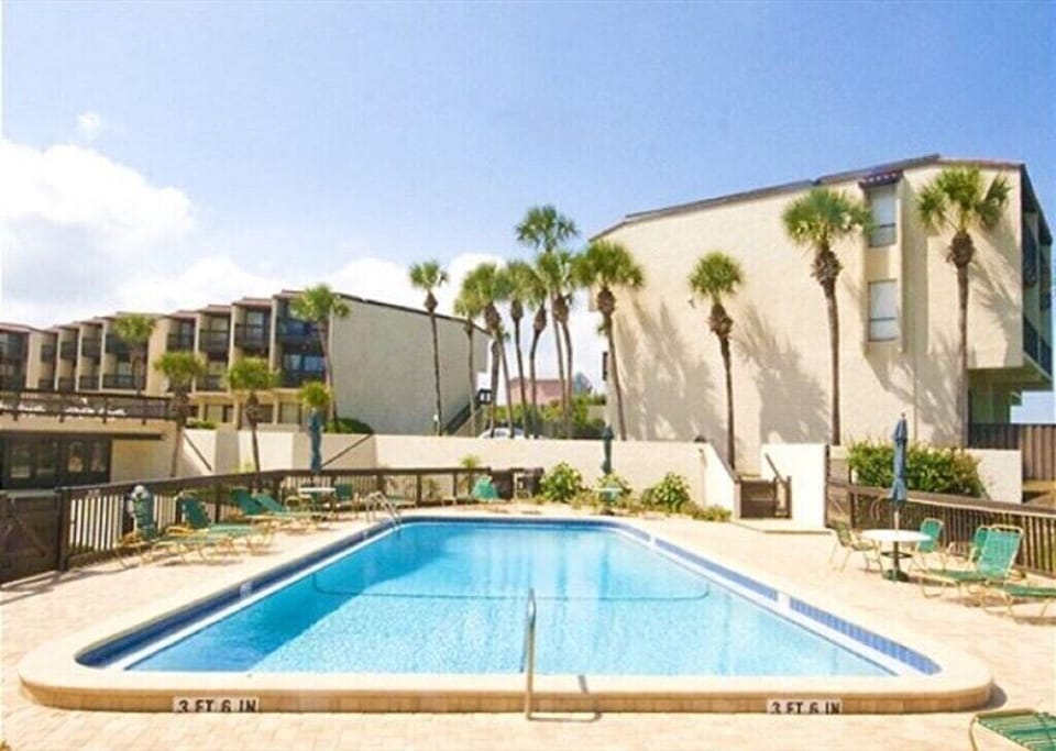 Inviting pool area with loungers, surrounded by palm trees perfect for relaxation.
