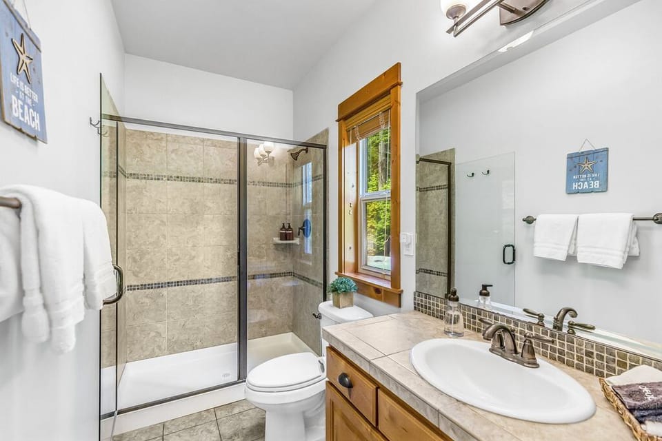En Suite Master Bathroom with Glass Door Intimate Shower Oversized Mirror And Wood Vanity