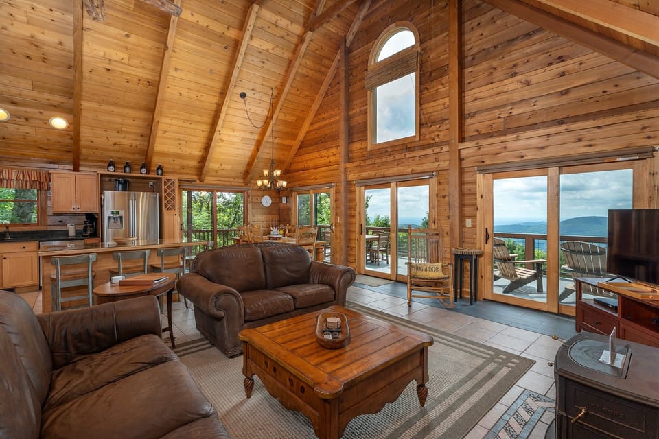 Living room with floor-to-ceiling mountain views, wood stove, and Smart TV.