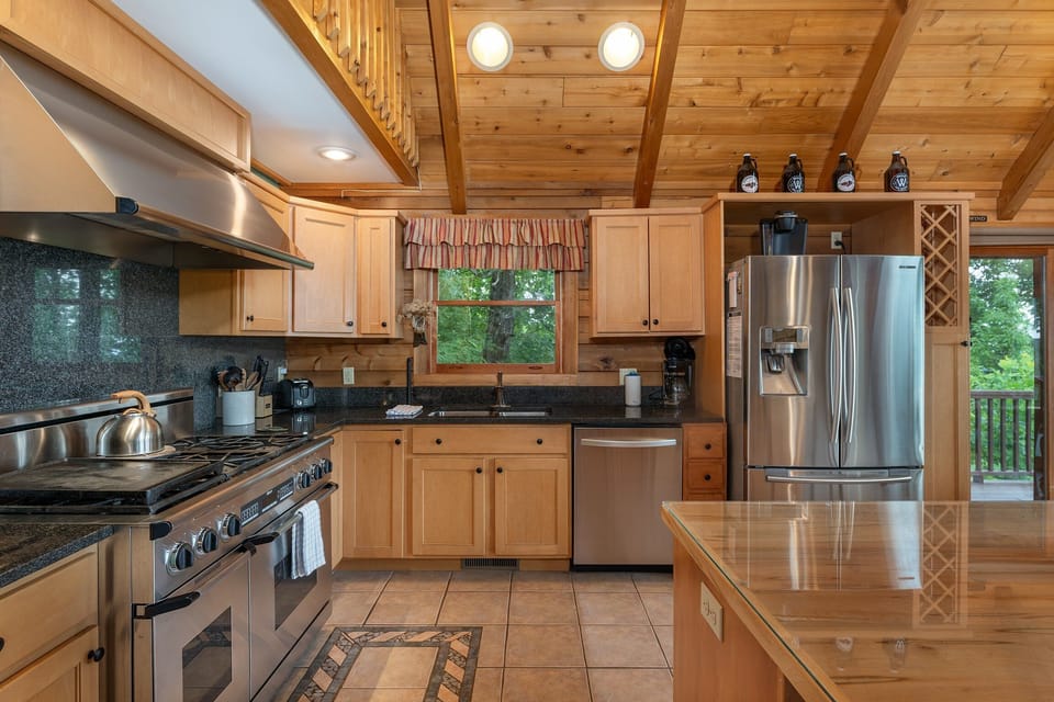 Gourmet kitchen with island seating for 4, 6-burner gas range, dishwasher, and drip-style coffeemaker.