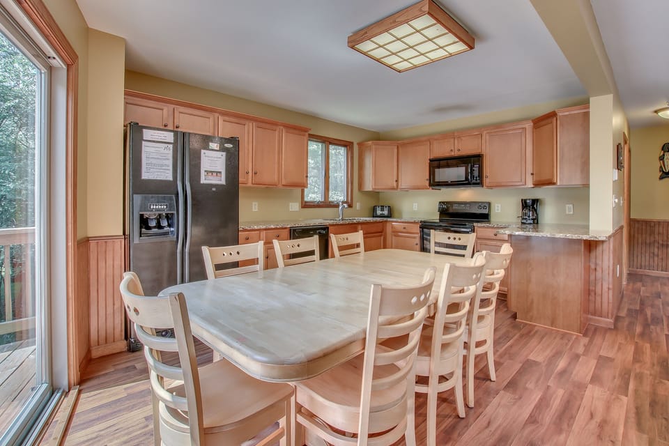 The kitchen with table and chairs, a double-door refrigerator, oven, and microwave.