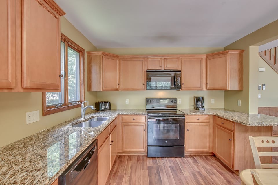 A picture of the kitchen, with the microwave, oven, sink, and dishwasher  in shot.