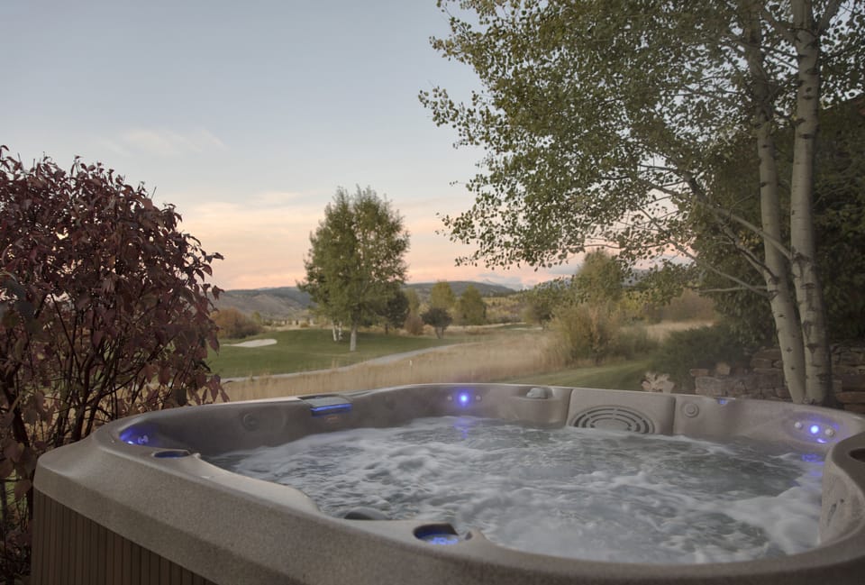 Unwind in your private hot tub as golden hour paints the sky, surrounded by lush gardens and rolling countryside views that stretch to distant mountains—pure tranquility awaits.