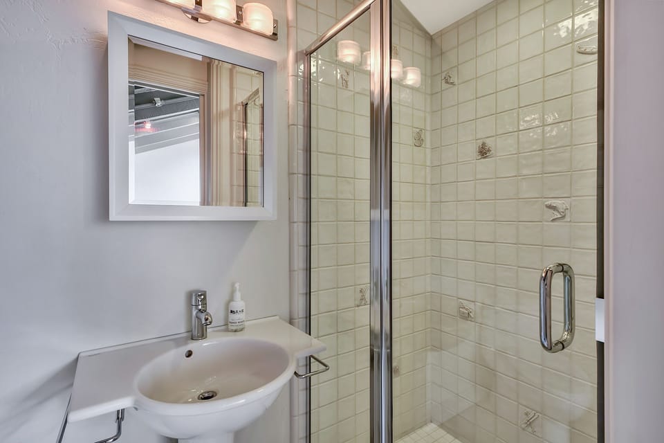 Step into your pristine bathroom featuring a spacious glass shower and sleek sink—perfect for refreshing after exploring.