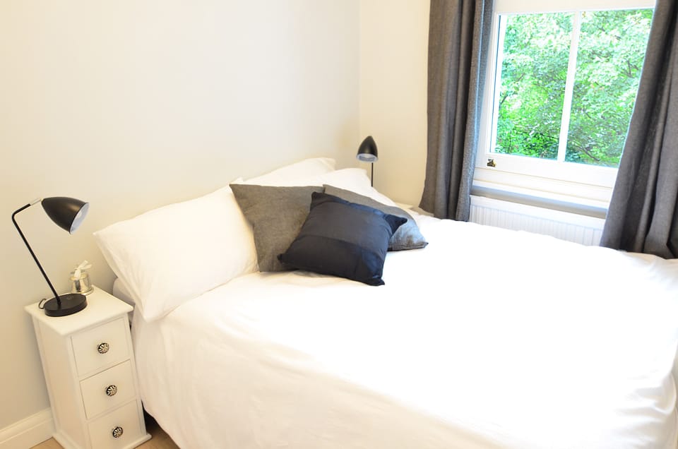 Cosy bedroom with double bed,cushions, bedside lamps and radiator 