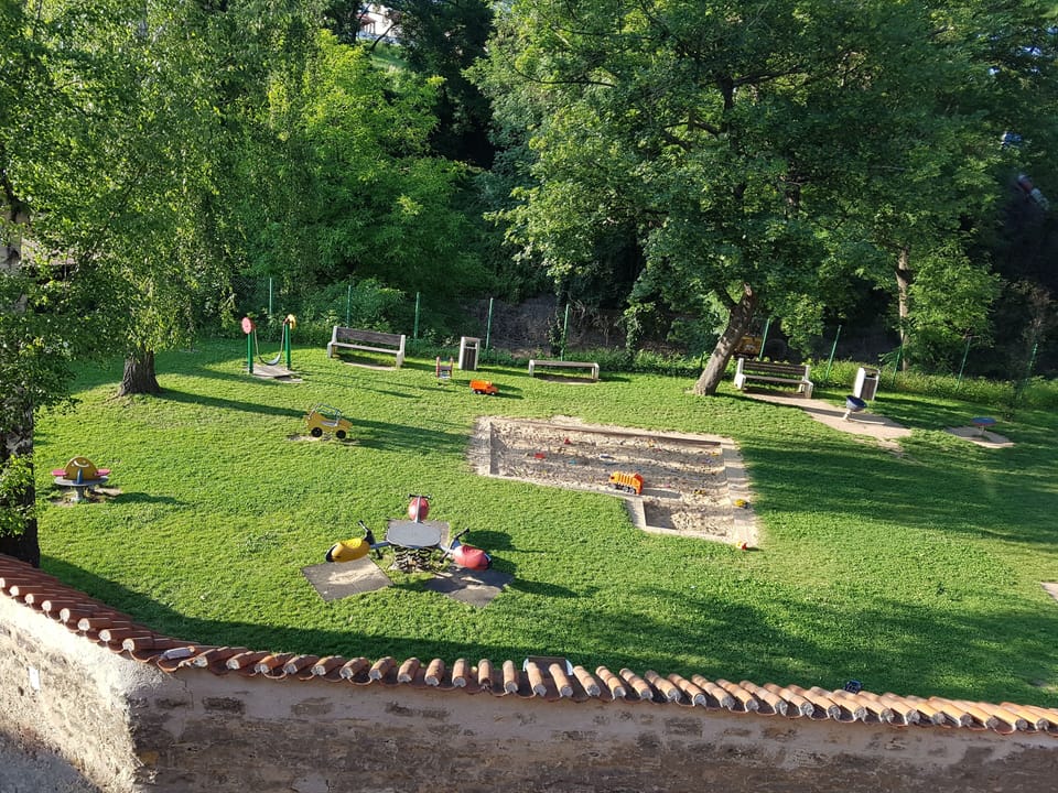Behind the wall there is a place for a picnic and a playground