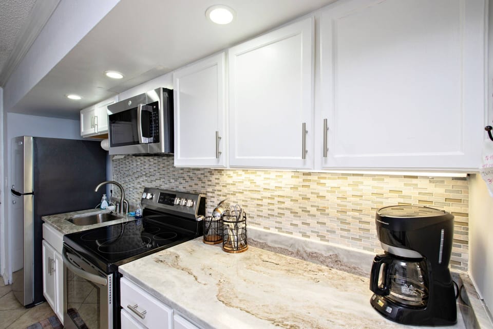 Kitchen includes a refrigerator, flat-burner glass stove / oven, microwave, toaster, coffee maker, cookware, plates, and utensils.