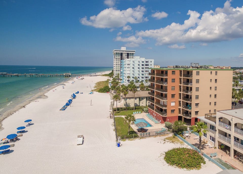Beachfront buildings and pristine white sand coastline with turquoise waters and resort amenities in a tropical setting.