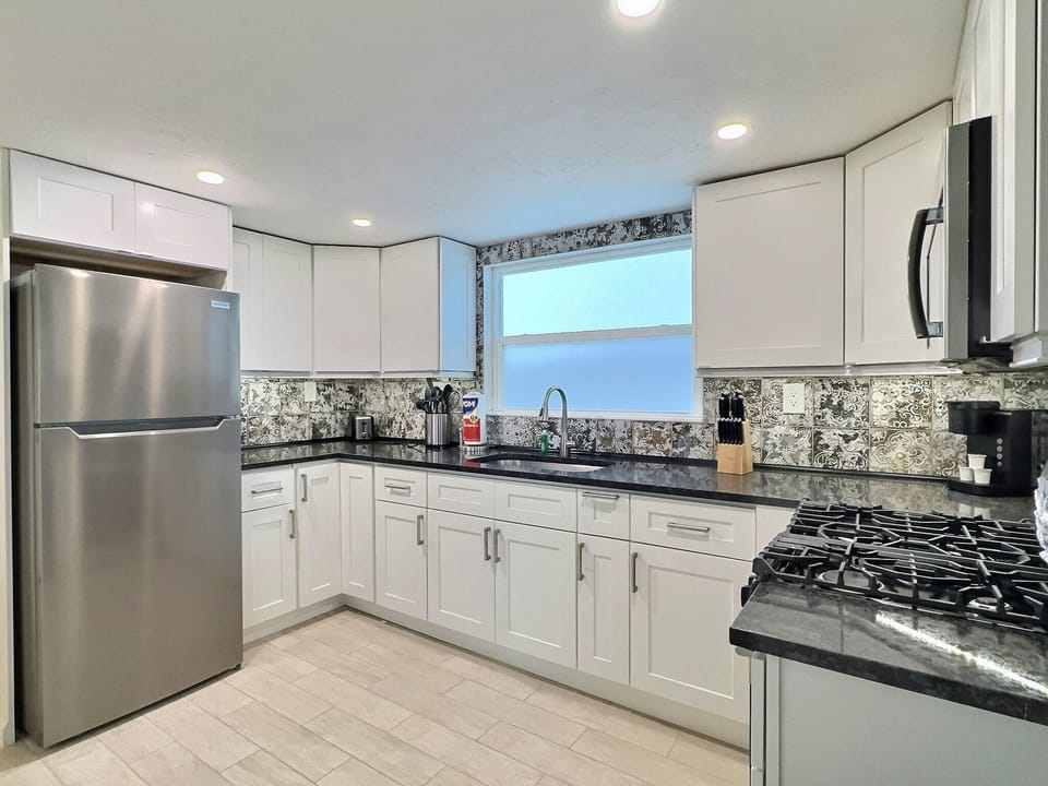 Kitchen with white cabinetry, stainless steel refrigerator, and tile backsplash