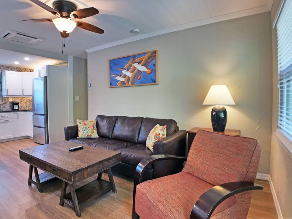 Living area with sofa, coffee table, floor lamp, and coastal wall art