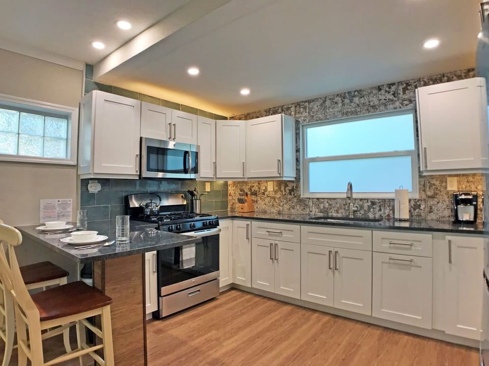 Kitchen from different angle with stainless appliances, white cabinets, and bar seating